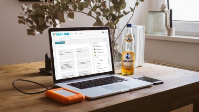 Photo of a notebook on a table. The screen shows Taskly's dashboard.